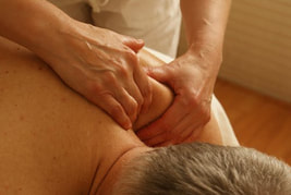 A picture of a man lying on a massage table receiving a deep tissue massage.